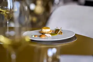 A plate of food on a table, with a wine glass next to it.