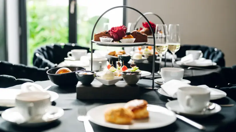 An attractively laid table with tiers of trifles, champagne glasses, cups and plates. 