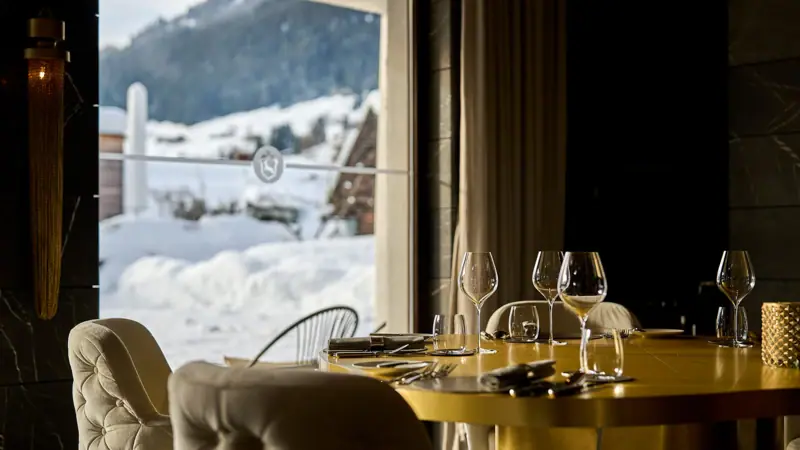 Restaurant A table with wine glasses and chairs in front of a window.