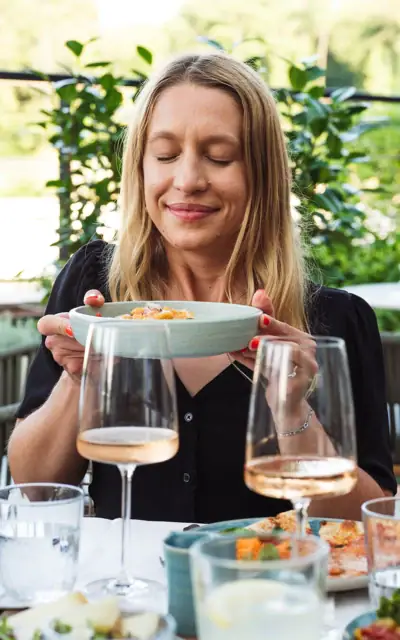 A woman smiling while holding a bowl of food.