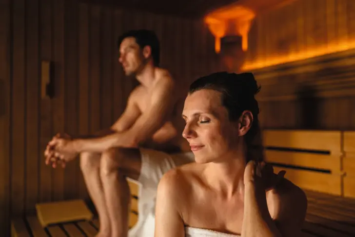 A man and a woman smiling in a sauna.