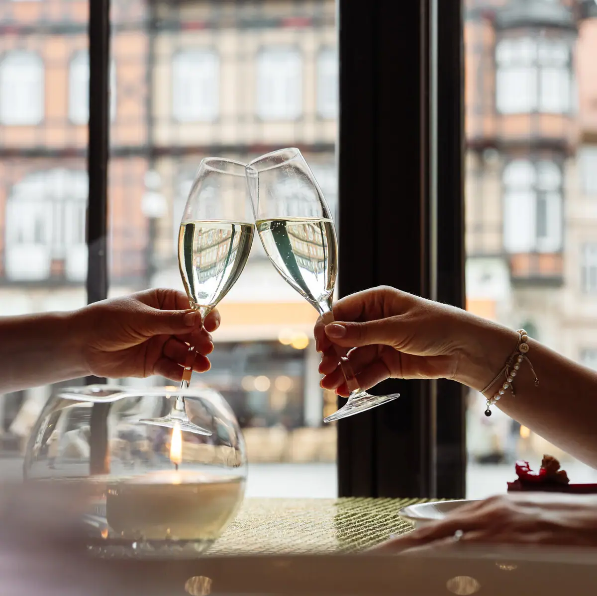 Two hands clink wine glasses.