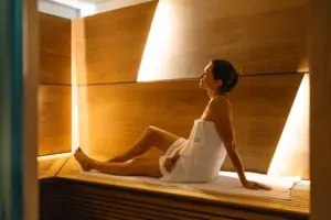 A woman wrapped in a towel is sitting on a bench.