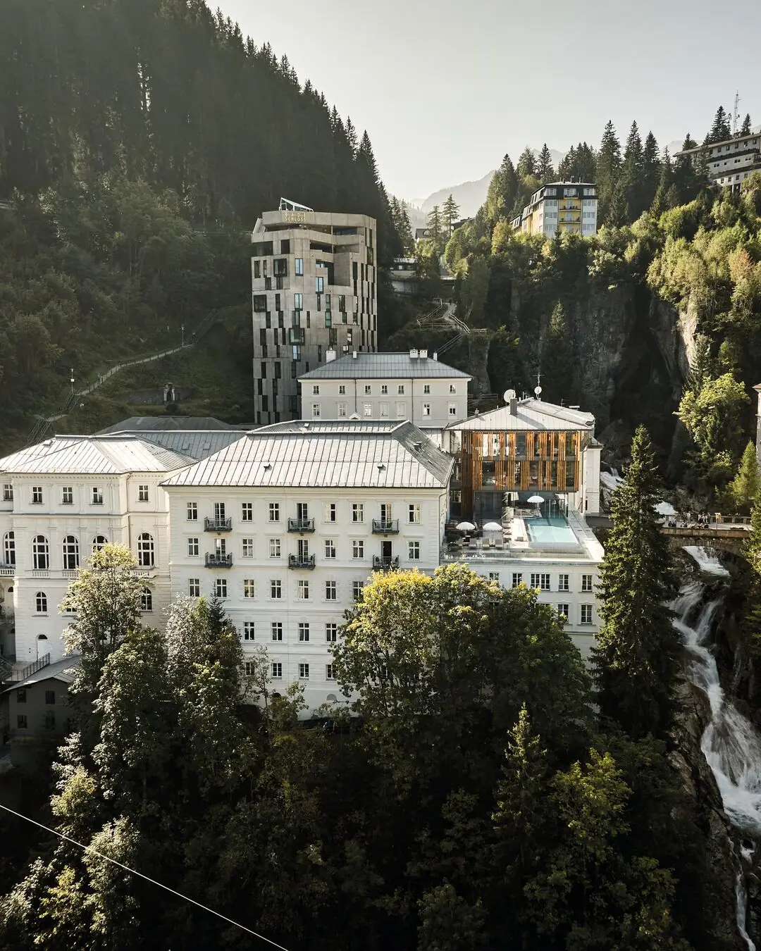 A group of buildings surrounded by trees with mountains in the background.