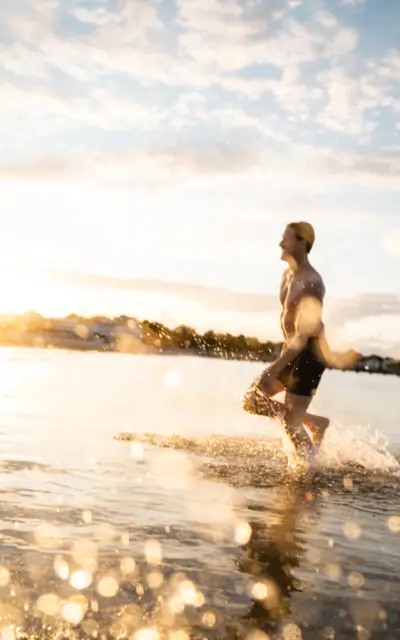 Man walking in the water on a sunny beach.