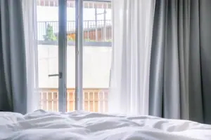 View obstructed A bed with white sheets and curtains.