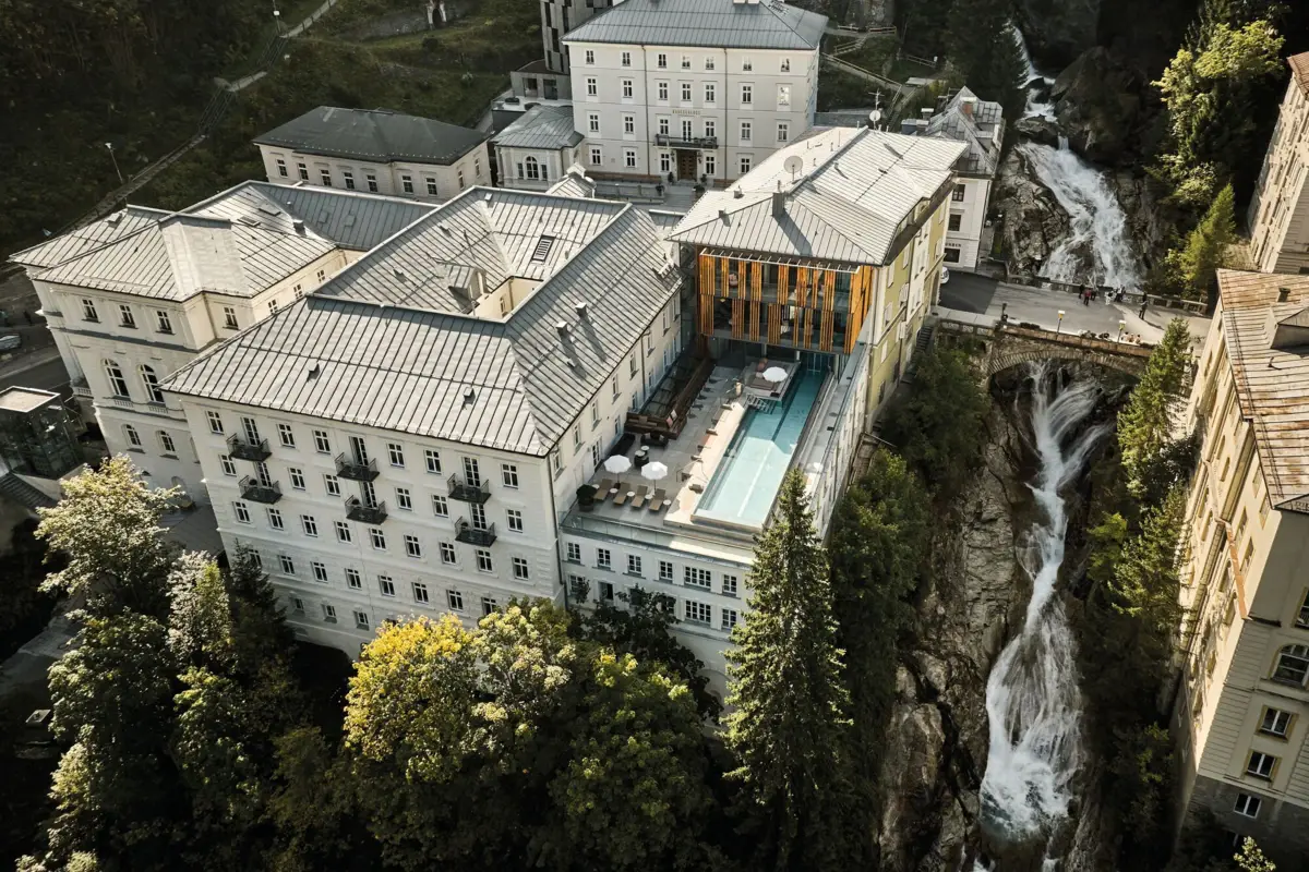 A building with a pool and a waterfall surrounded by trees.