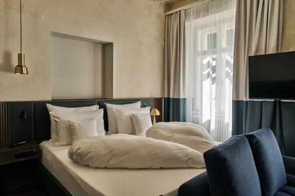 A neatly made bed with several pillows and a lamp in a well-designed hotel room.