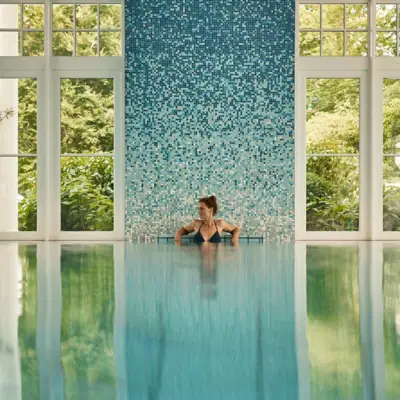 A woman swimming in a pool with clear water reflecting light.