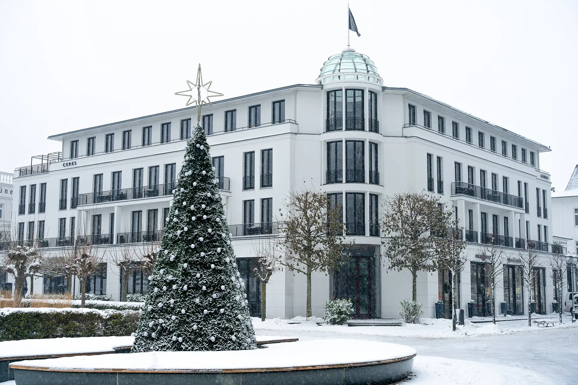 Winter view of Ceres am Meer hotel by the Baltic Sea with snow and Christmas tree.