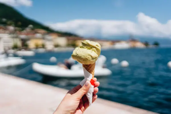 Ice cream in Bardolino A hand is holding an ice cream in a cone, with a boat in the background.