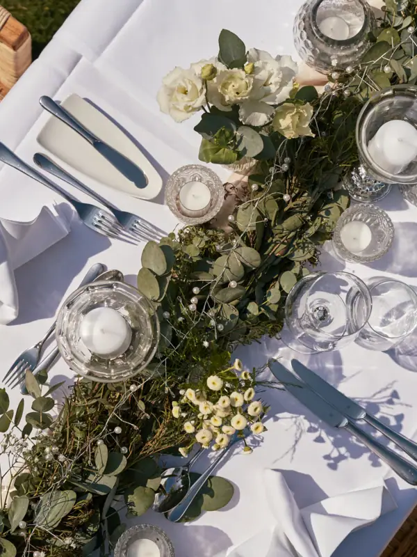 A table with a white tablecloth adorned with candles and a floral arrangement.