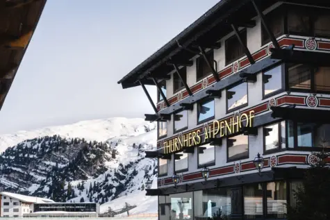 A building with a sign on the side, surrounded by snow and mountains.