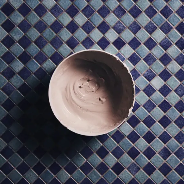 A bowl of clay on a tile surface.