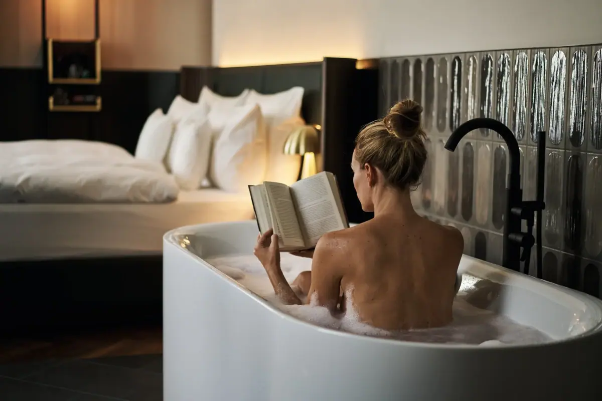 A woman in a bath is reading a book at A-ROSA Bad Gastein.