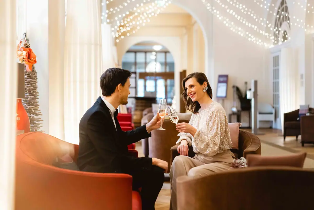 Cheers A man and woman sitting in chairs, holding wine glasses indoors.
