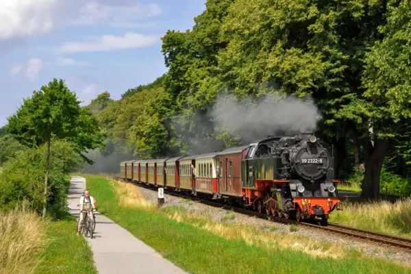 Ein Mann fährt mit einem Fahrrad neben einem Zug.