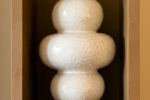 White vase on a wooden shelf.