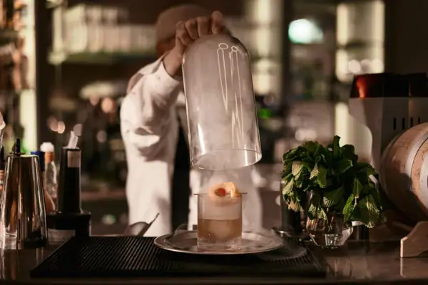 A person pouring a glass into a drink indoors.