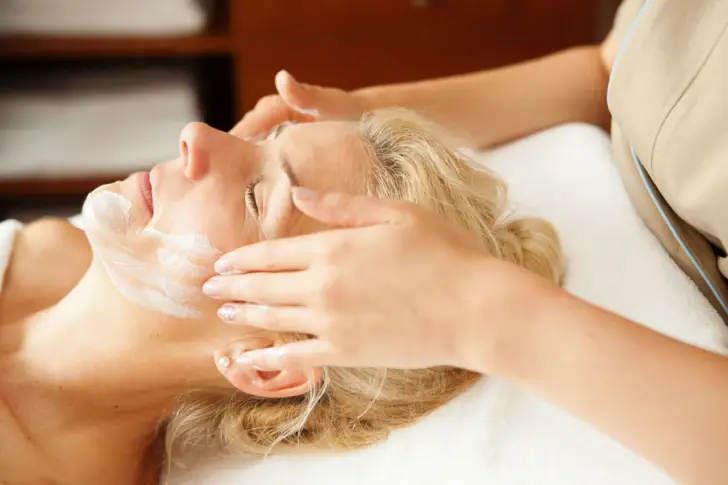 Woman receives a facial massage in an interior room.