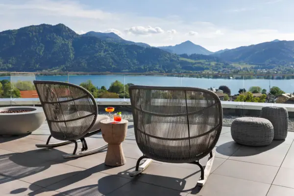 A chair and table on the NI BAR rooftop terrace overlooking a lake.