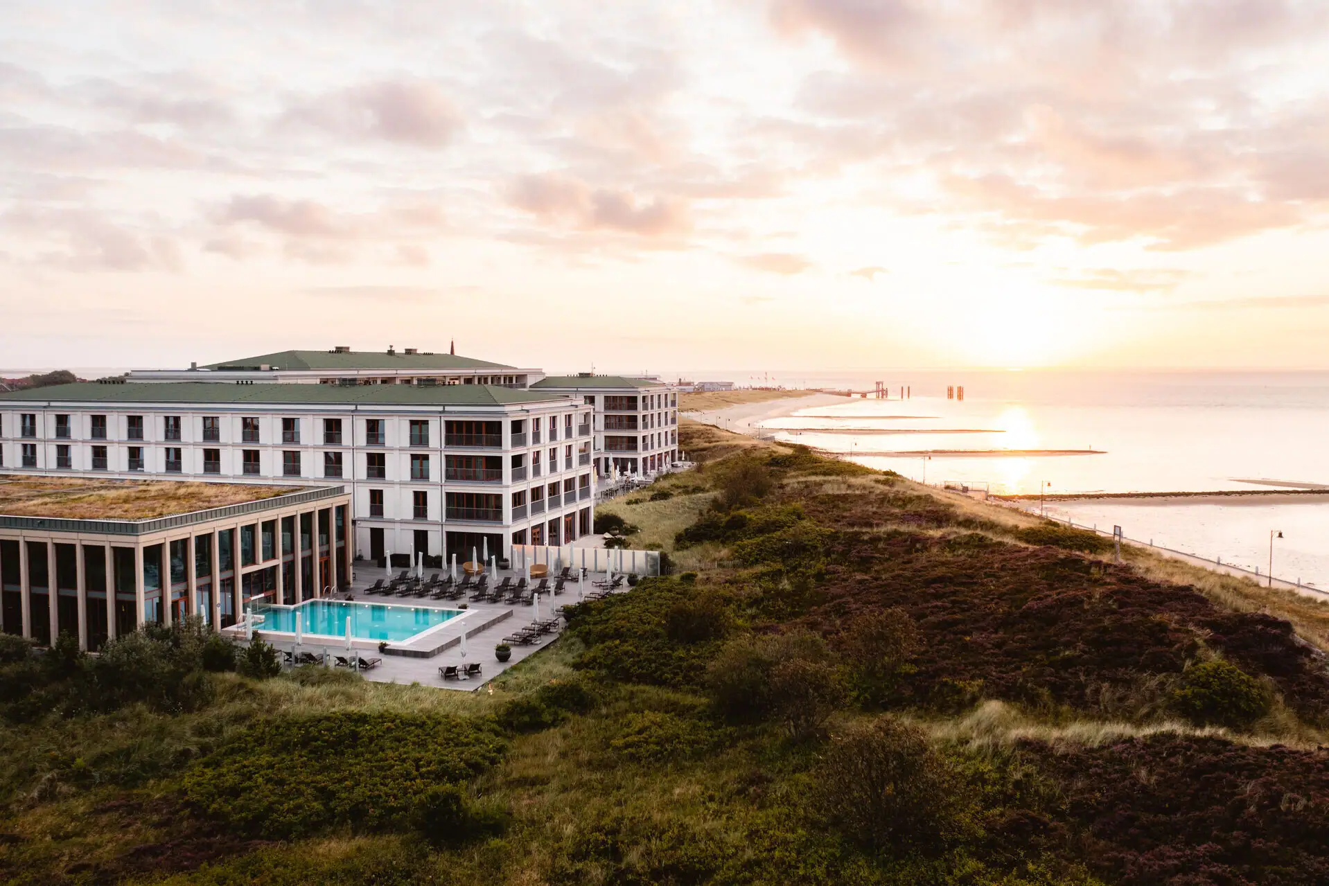 A-ROSA Sylt at sunset overlooking dunes, beach and North Sea coastline.