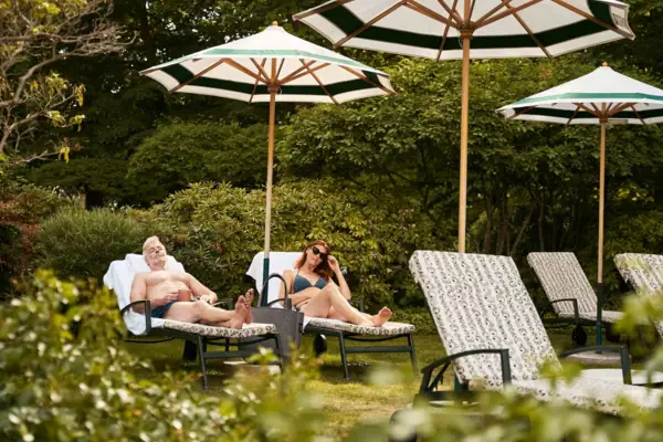 A man and woman sitting on lounge chairs under umbrellas.