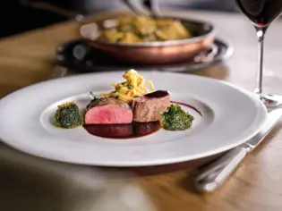 Plate with food and wine glass on a table.