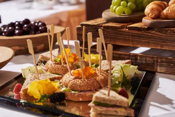 A tray of sandwiches with fruit on a table.