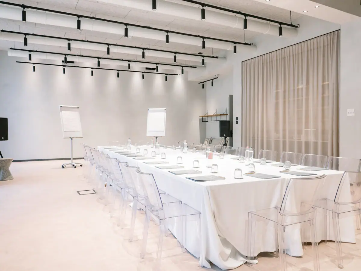 Creavista im A-ROSA Gardasee Ein Tagungsraum mit einem langen Tisch und Stühlen. Der Tisch ist eingedeckt mit Gläsern, Wasserflaschen und Tagungsmaterial.