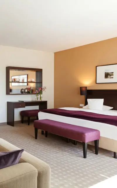 An elegant hotel room with a bed cosmetic desk and sofa. 