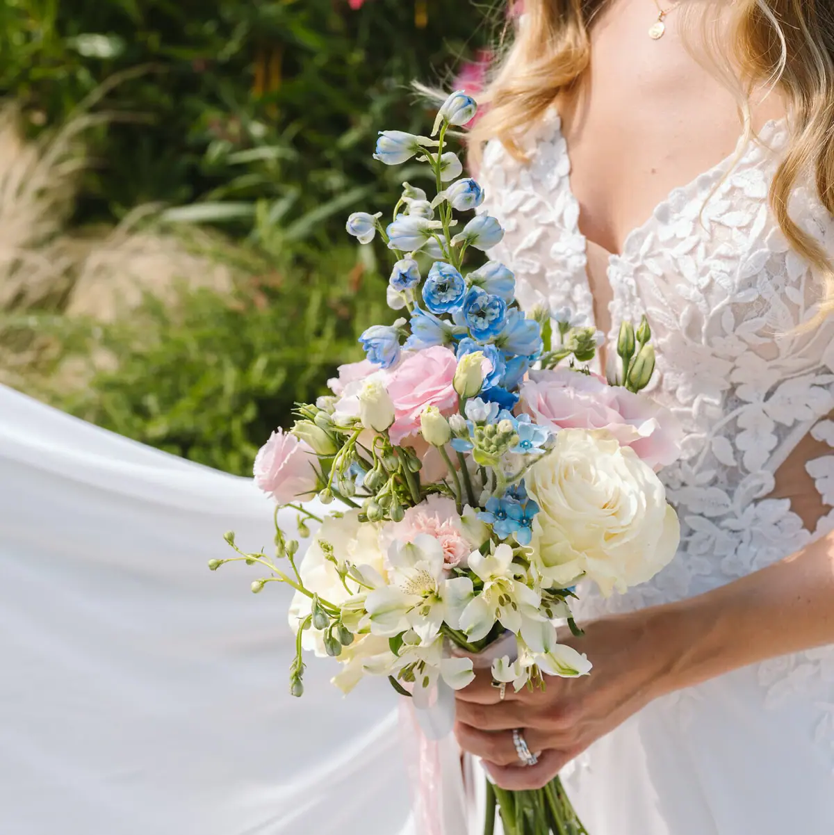 A woman in a white wedding dress is holding a bouquet of flowers at a wedding on Lake Tegernsee.