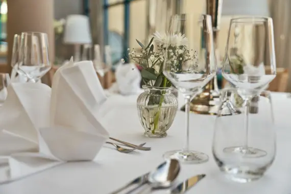 Elegantly set dining table with wine glasses and a vase of flowers.