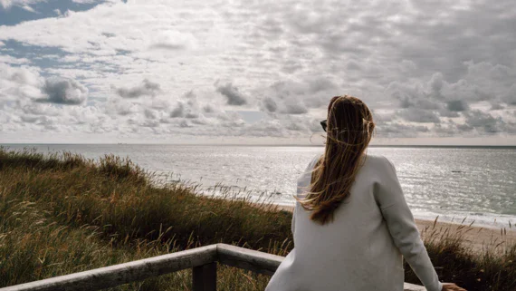 A woman in a cardigan looking out over the ocean.