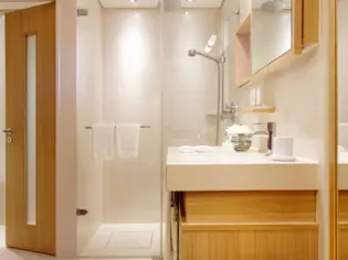 A bright bathroom with a shower and washbasin.