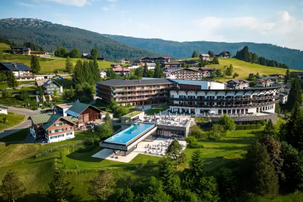 A-ROSA Ifen Hotel Kleinwalsertal Das A-ROSA Ifen Hotel im Kleinwalsertal mit großen Outdoor-Pool inmitten eines Berg-Dorfes.