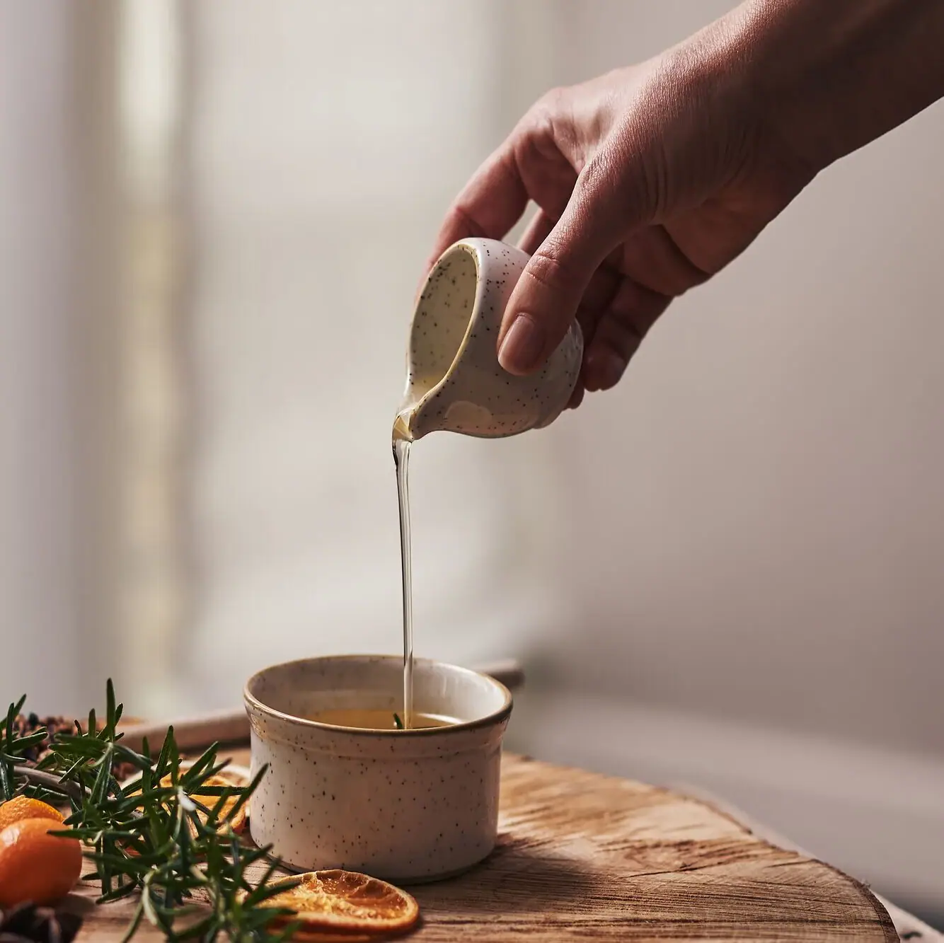 A person pouring liquid into a cup indoors.