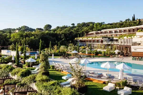 Swimming pool with parasols and sun loungers in front of a building.