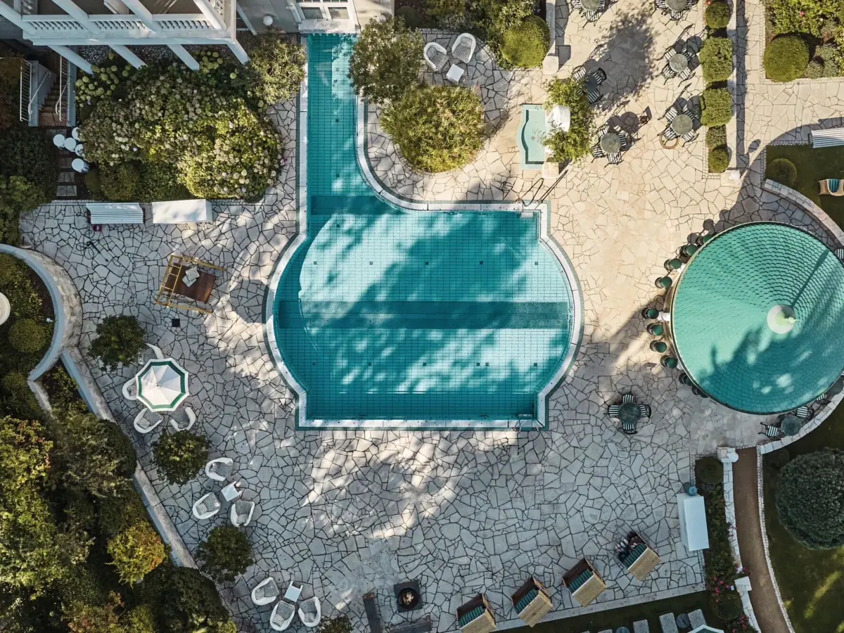 Schwimmbecken im Garten mit Bäumen im Hintergrund.