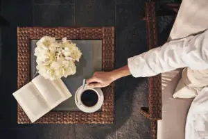 A person is holding a cup of coffee and a book.