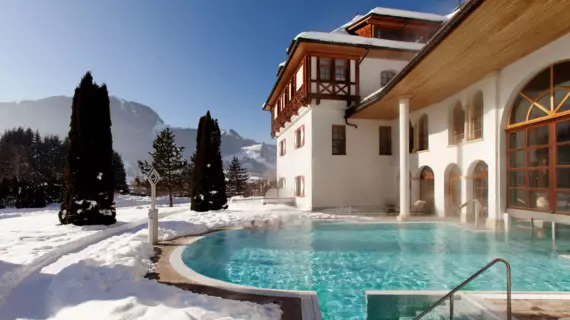 A warm steaming outdoor hotel pool in snowy landscapes while the sun is out. 