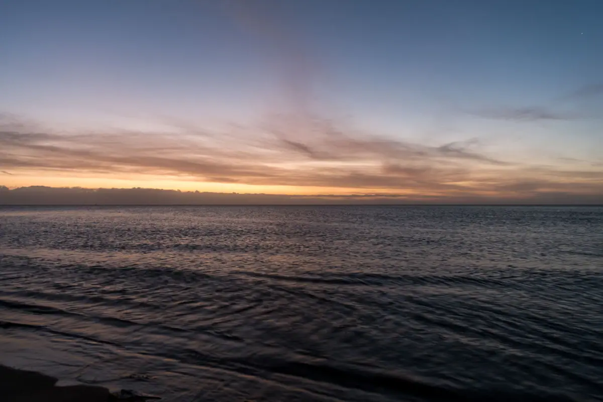 sunset Water at sunset with clouds in the sky