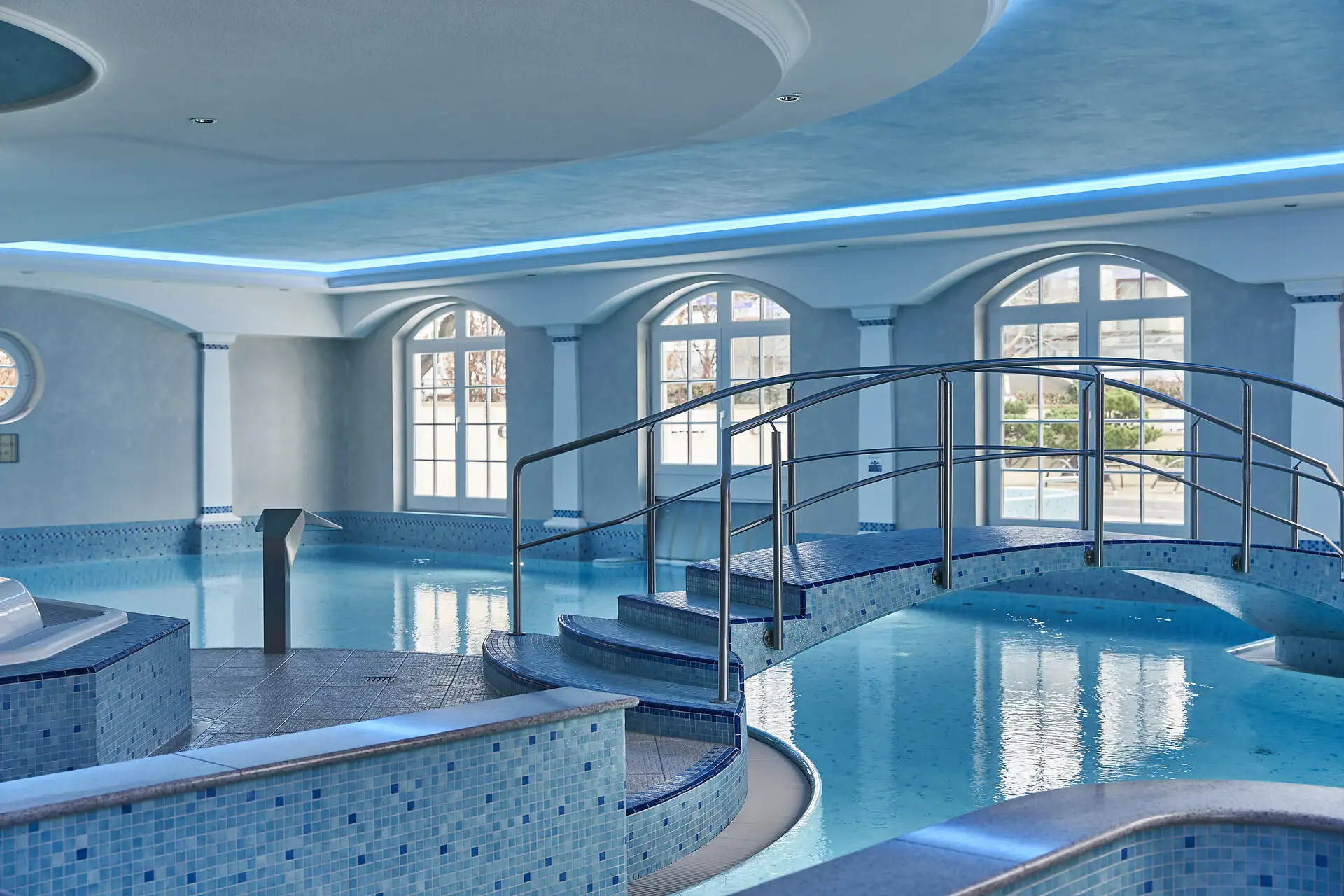 Pool Area A swimming pool with a curved walkway leading to it indoors.