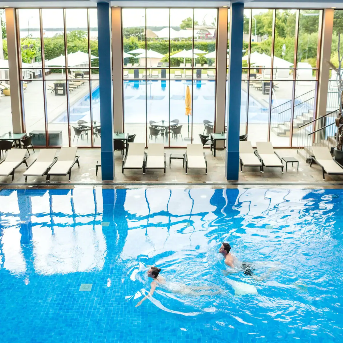 A man and a woman are swimming in a swimming pool.