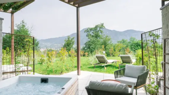 Whirlpool and chairs on a patio with mountain views in the background.