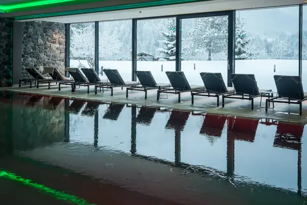 A swimming pool with chairs in front of a large window.