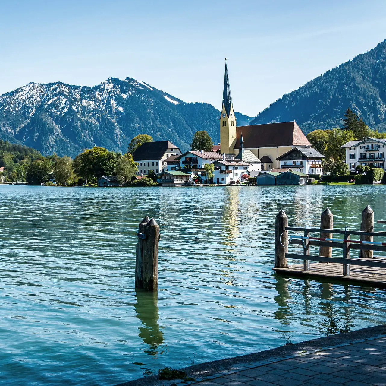 A lake with a church and mountains in the background.