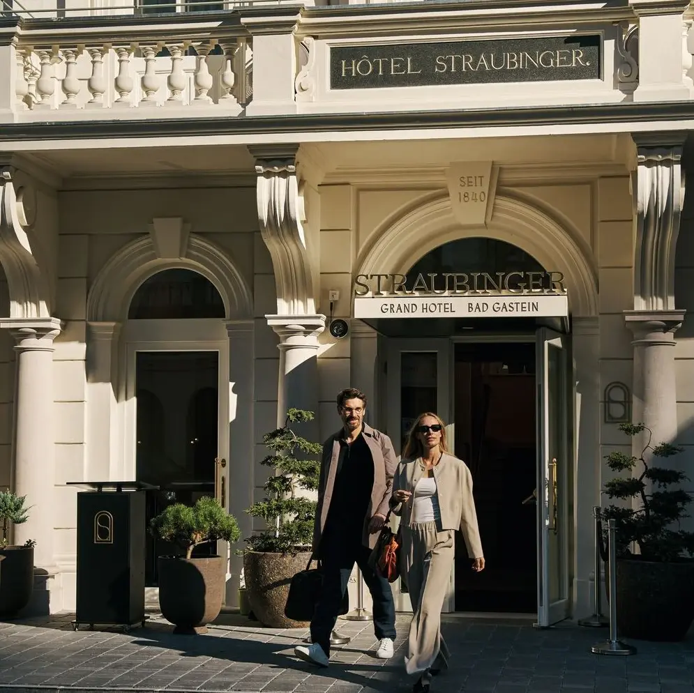 A man and woman walking in front of a hotel building.