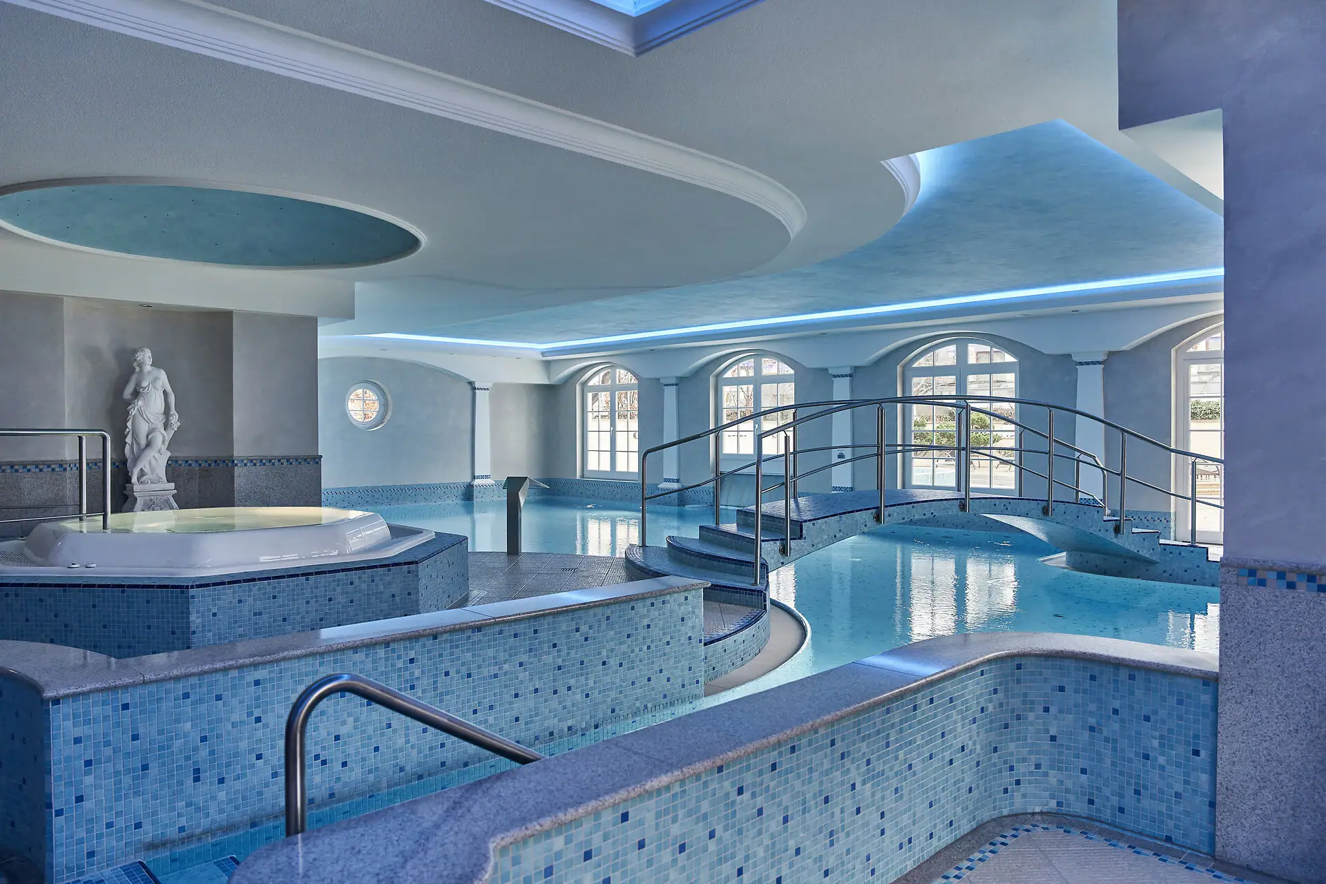 Pool Area A large indoor pool with a hot tub and stairs.