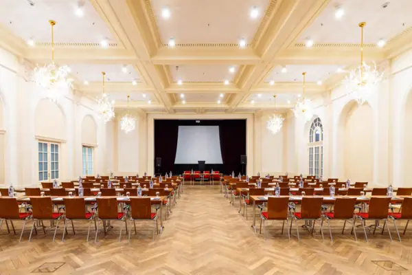 A hall with lots of chairs and a projection screen at A-ROSA Travemünde.